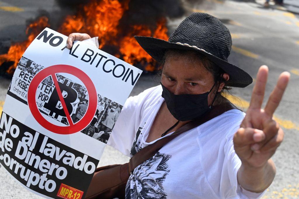 Mujer con cartel contra bitcoin.