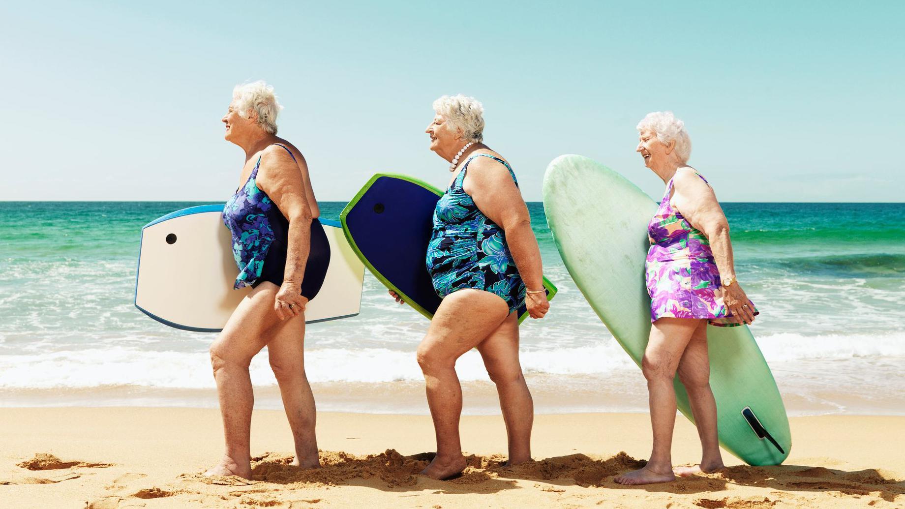 Tres mujeres mayores con tablas de surf