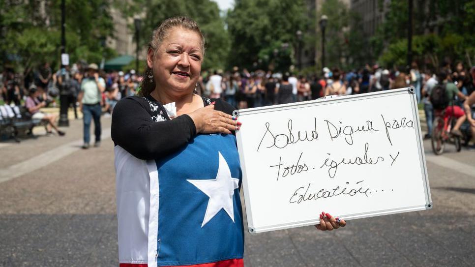 Manifestante sostiene un cartel pidiendo salud digna para todos.