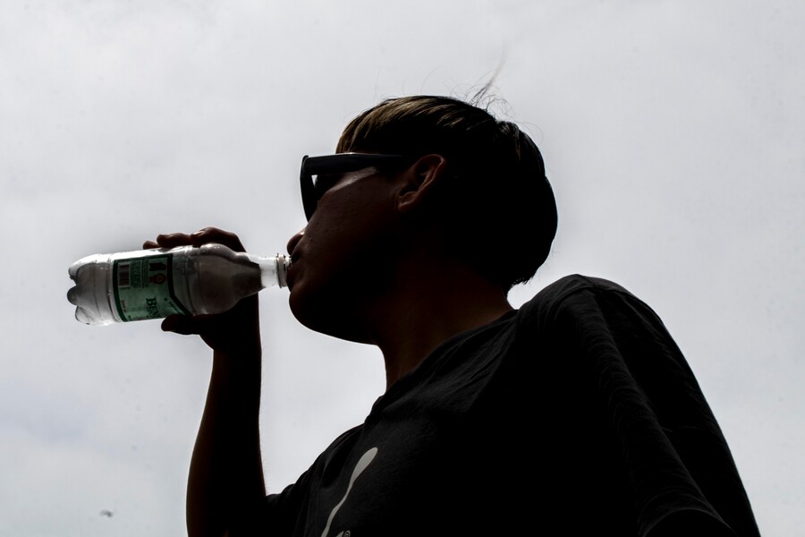 Persona con calor tomando agua. Altas temperaturas.