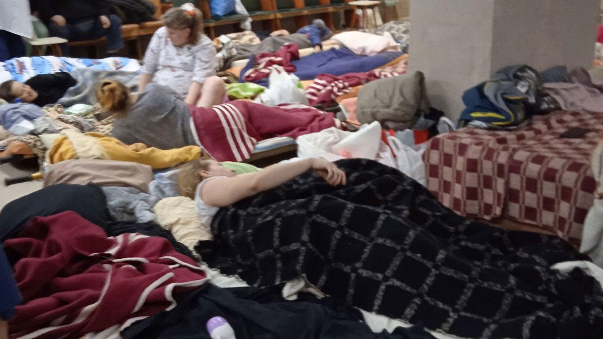 Personas acostadas en camas improvisadas sobre el suelo del