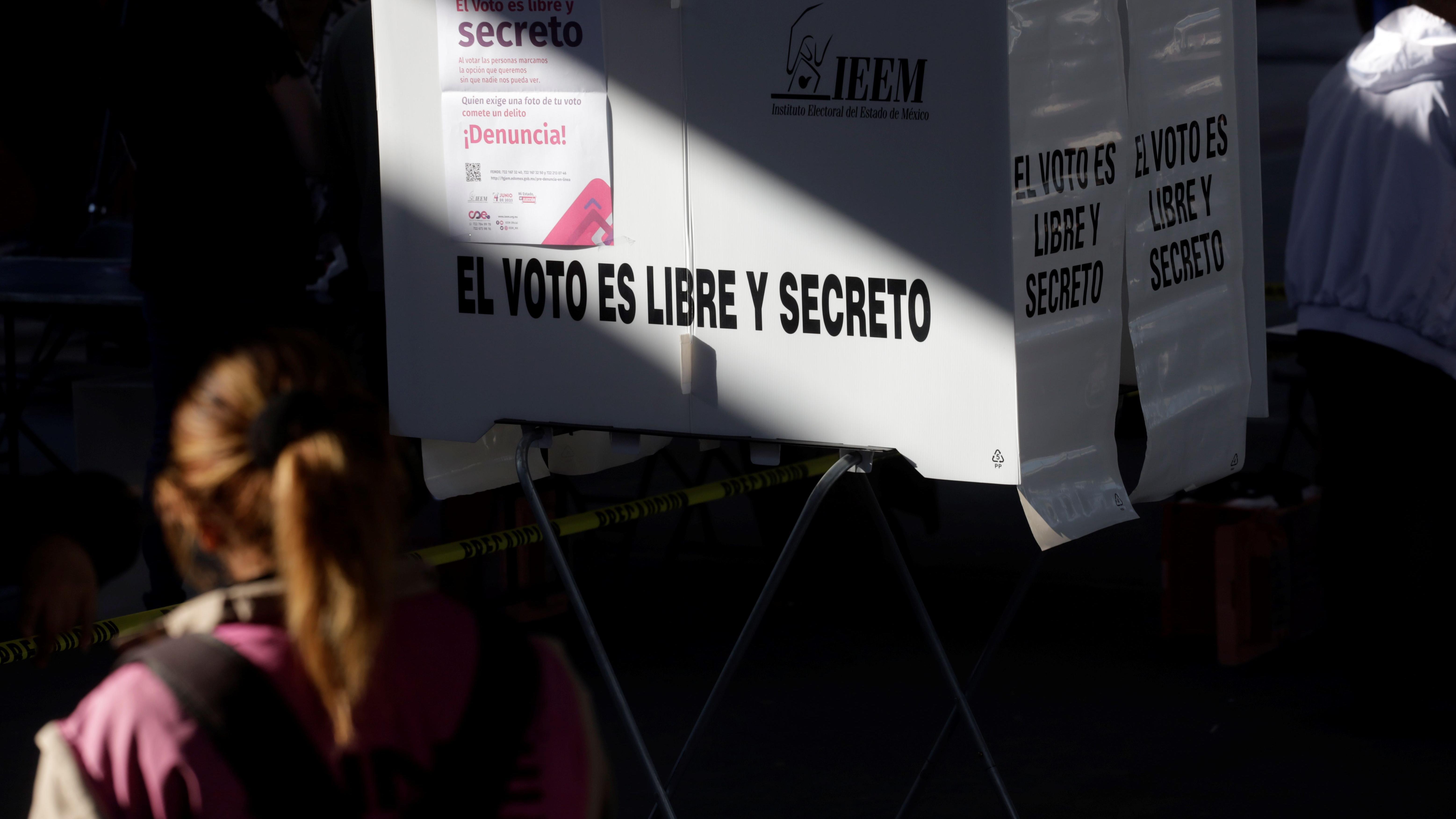 Una mujer se aproxima a una urna que lee "el voto es libre y secreto" en México.