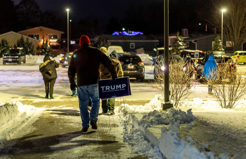 Persona con un cartel a favor de Trump camina sobre la nieve 