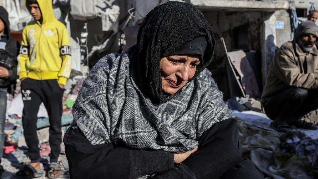 una mujer llora entre edificios destruidos en Palestina