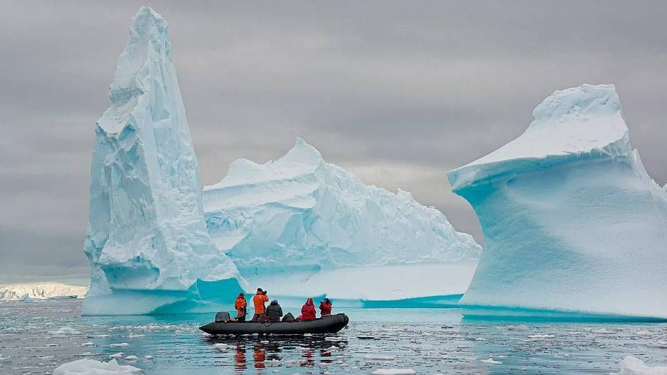 Turistas en un bote inflable Zodiac tomando fotos de icebergs
