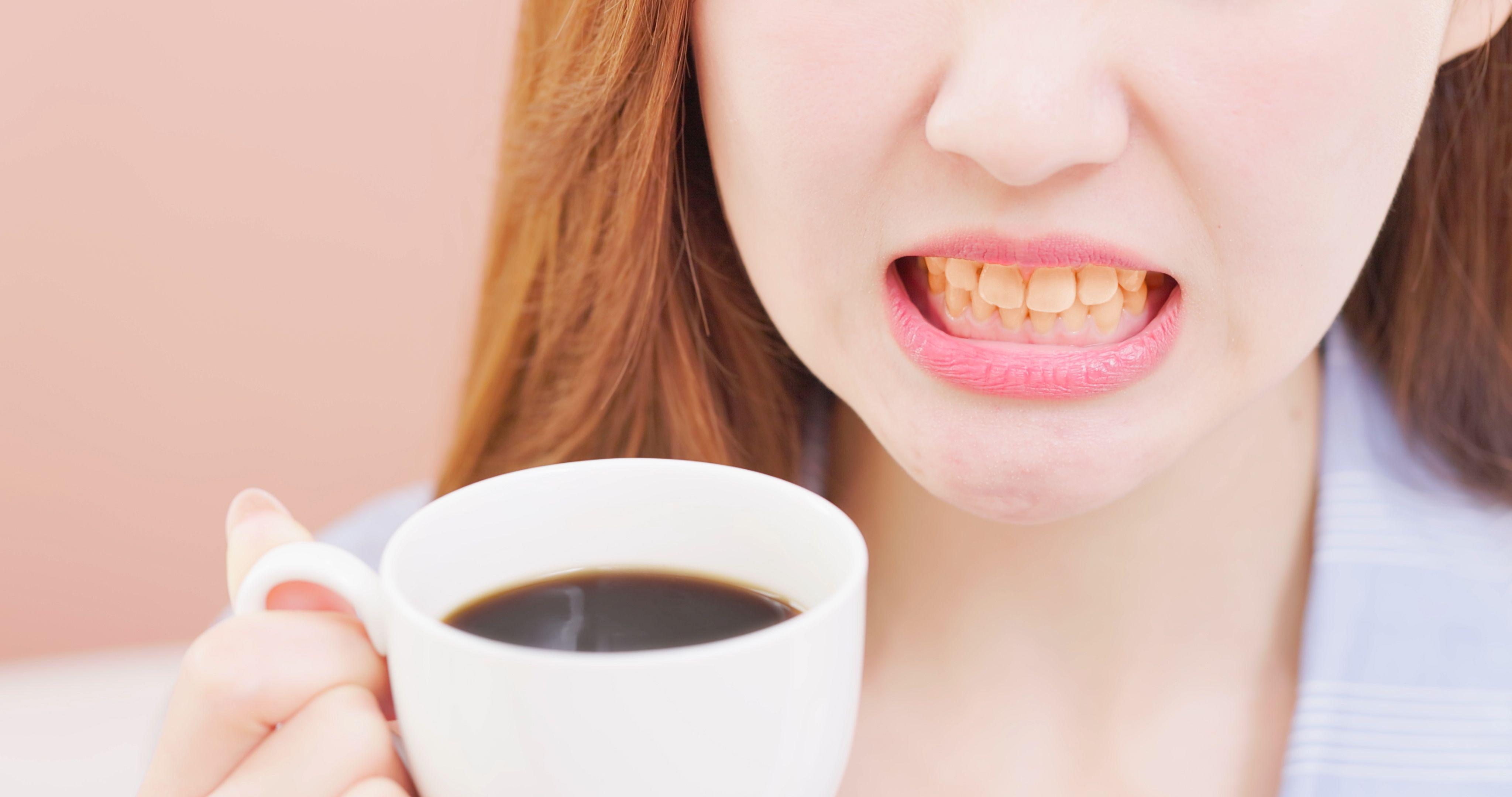 Una mujer con los dientes amarillos sostiene una taza de café