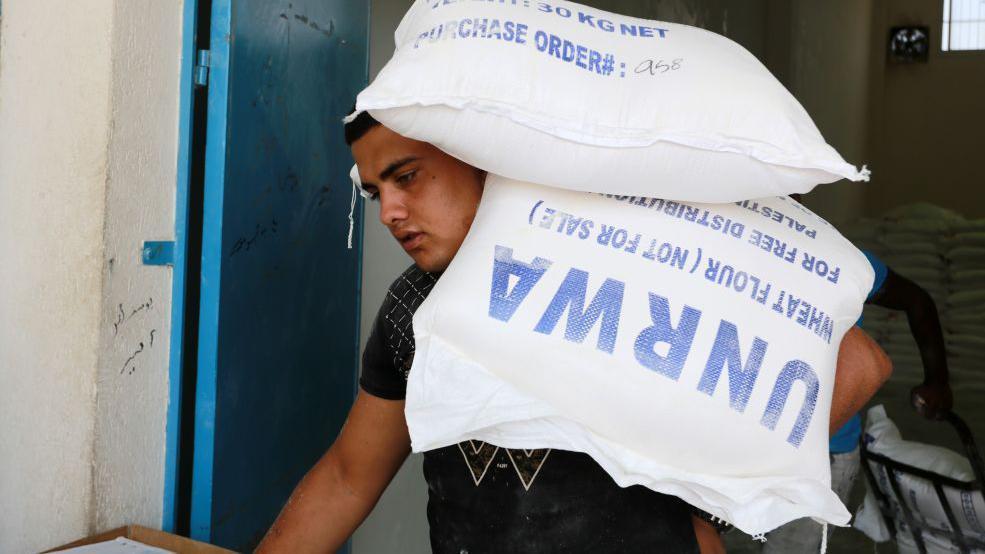 Un hombre carga un saco de harina donado por la UNRWA.