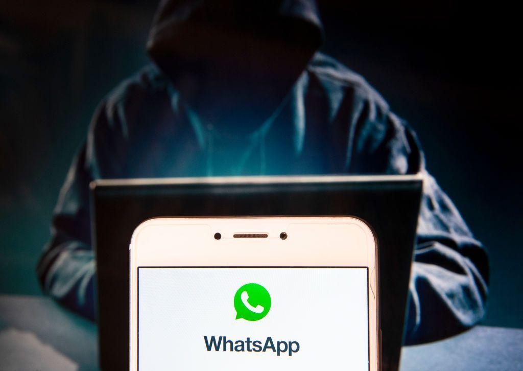 Una ilustración de un hacker y un teléfono con WhatsApp