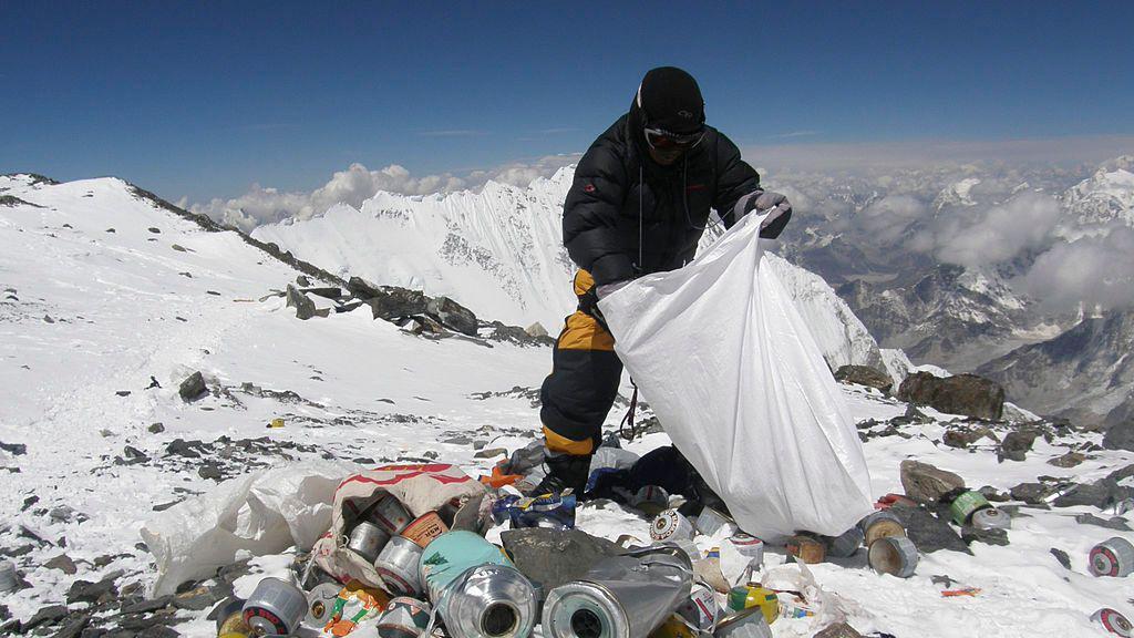 Un escalador recoge basura en el camino de ascenso al Monte Everest.