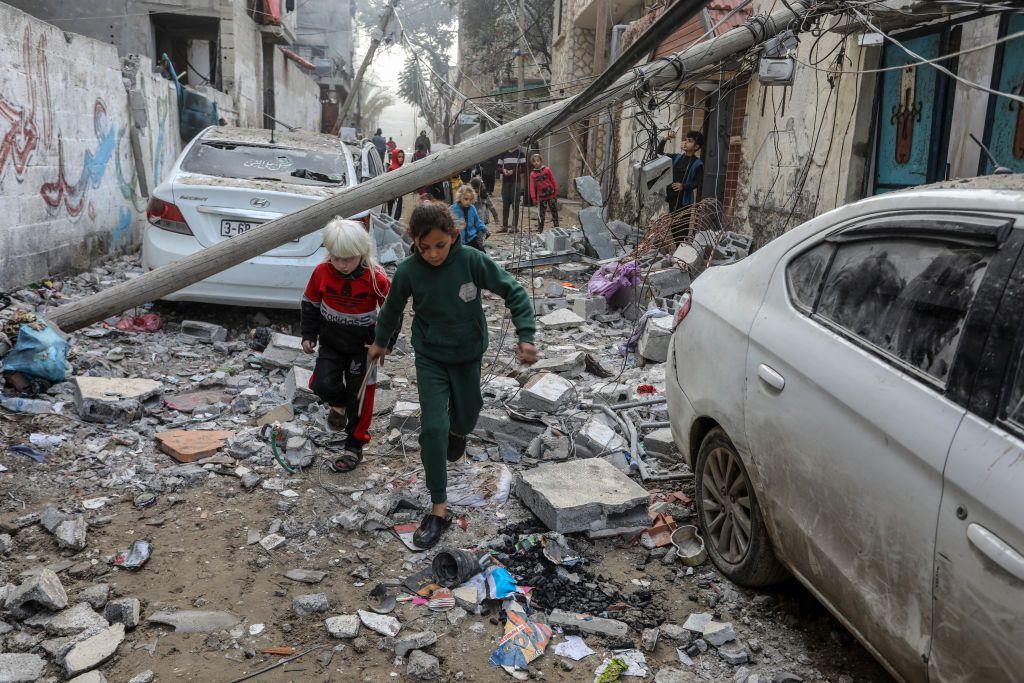 Niños entre los escombros de un edificio impactado por un cohete israelí