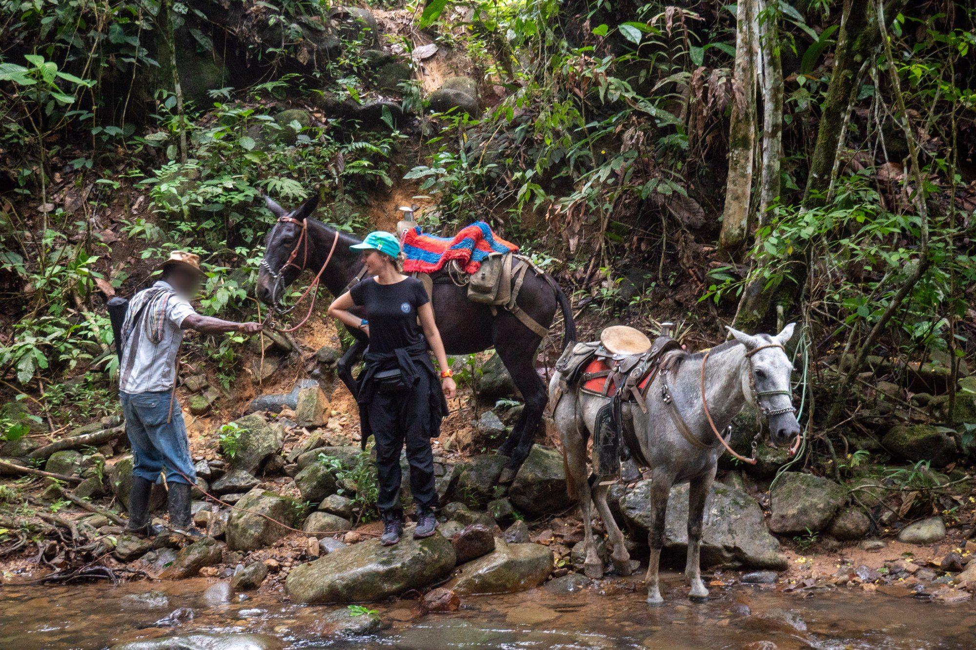 Adriana con un guía y caballos frente al remanso de un río