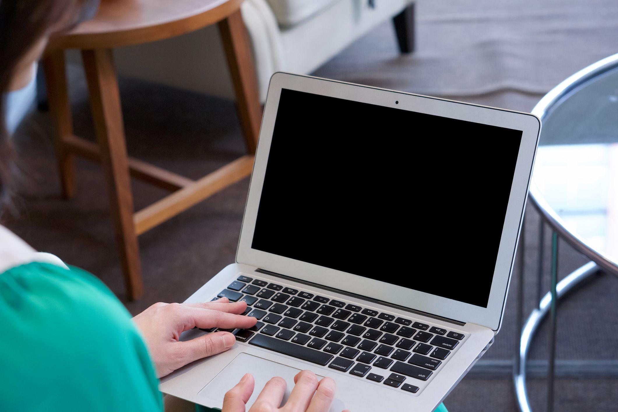 Una mujer usando una computadora cuya pantalla está en negro