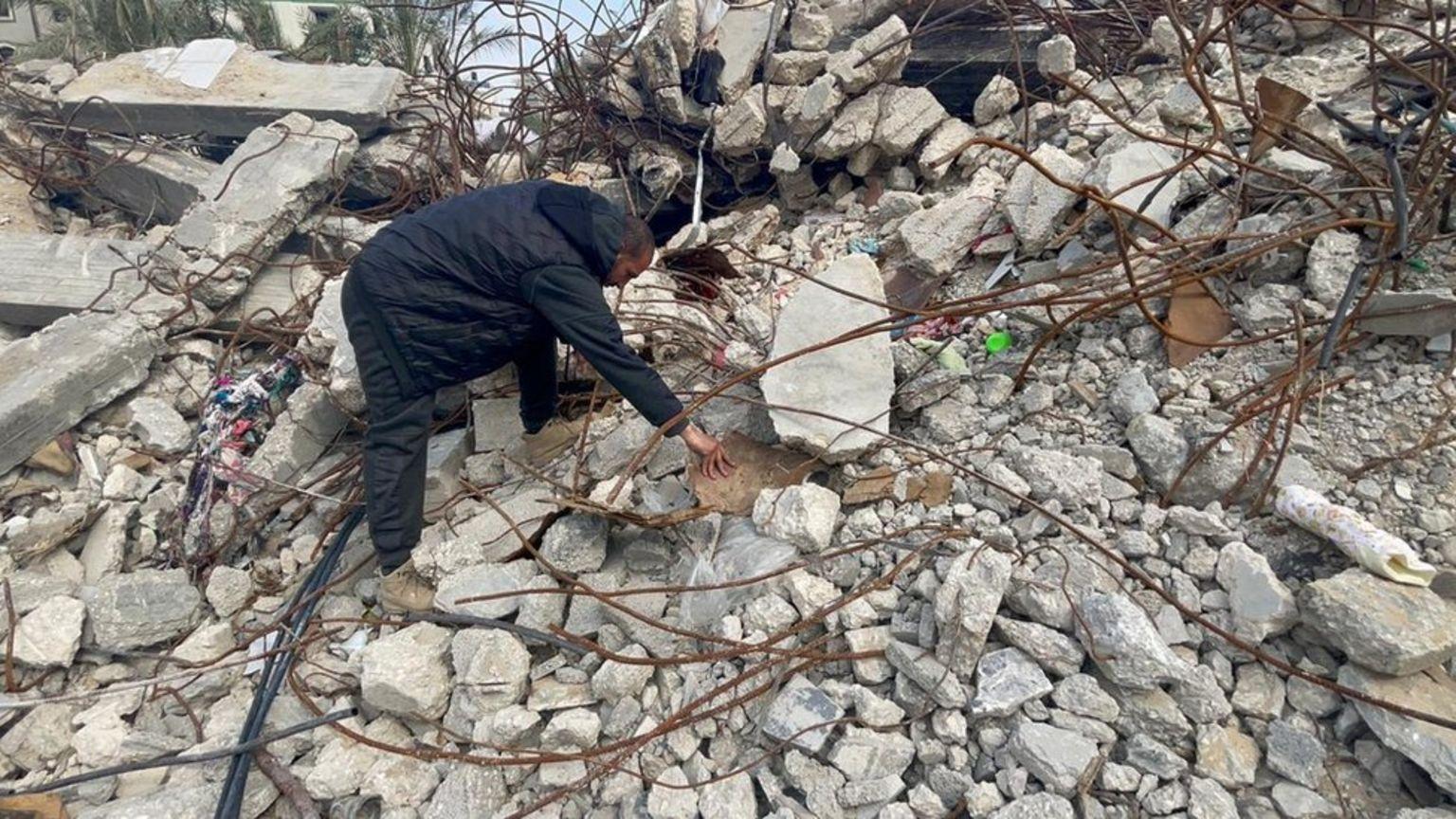 Una persona busca bajo los escombros de la casa destruida en Gaza