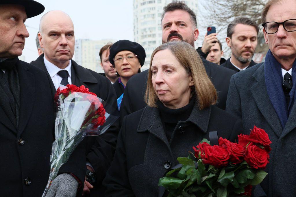 La embajadora de EEUU portando flores rojas.