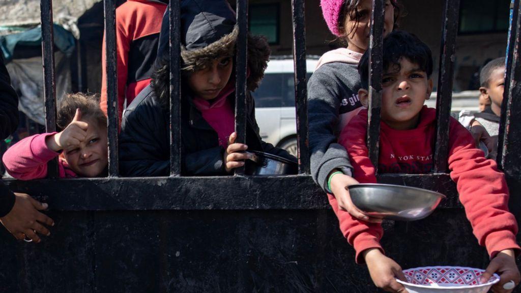 Niños sostienen platos vacíos en Gaza