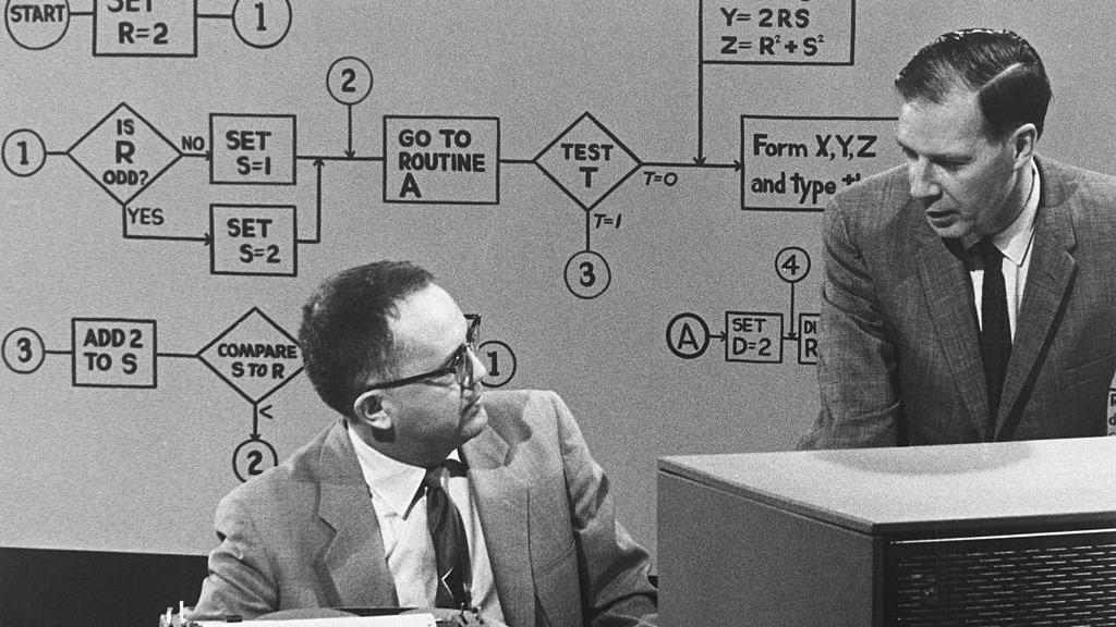 Dos hombres discuten sobre programas computacionales en 1962.