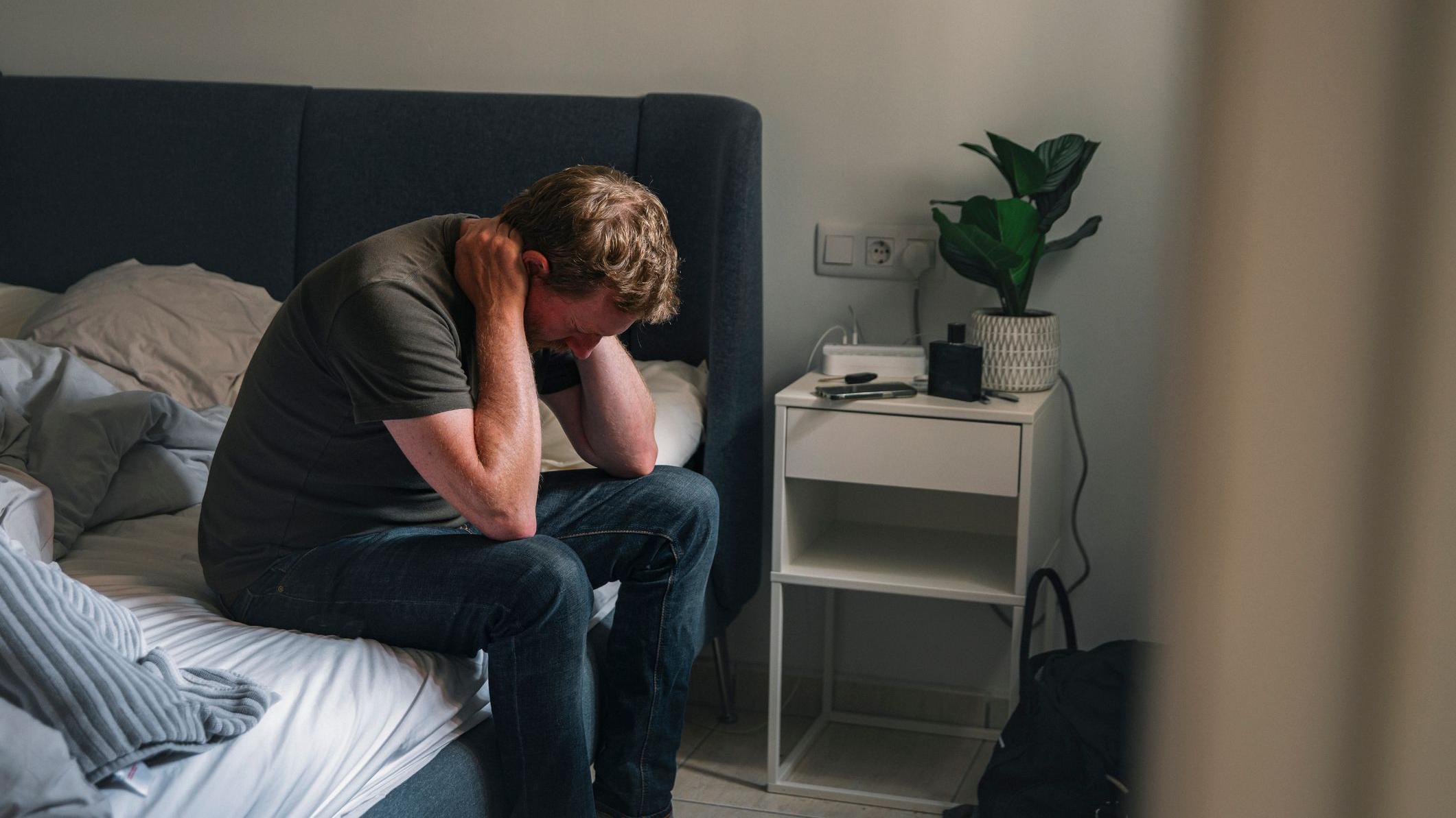 hombre solo en su habitación se toca la cabeza
