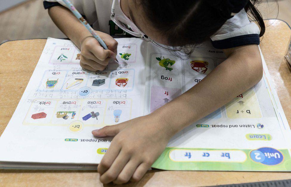 Una niña coreana hace un ejercicio en su libro de inglés