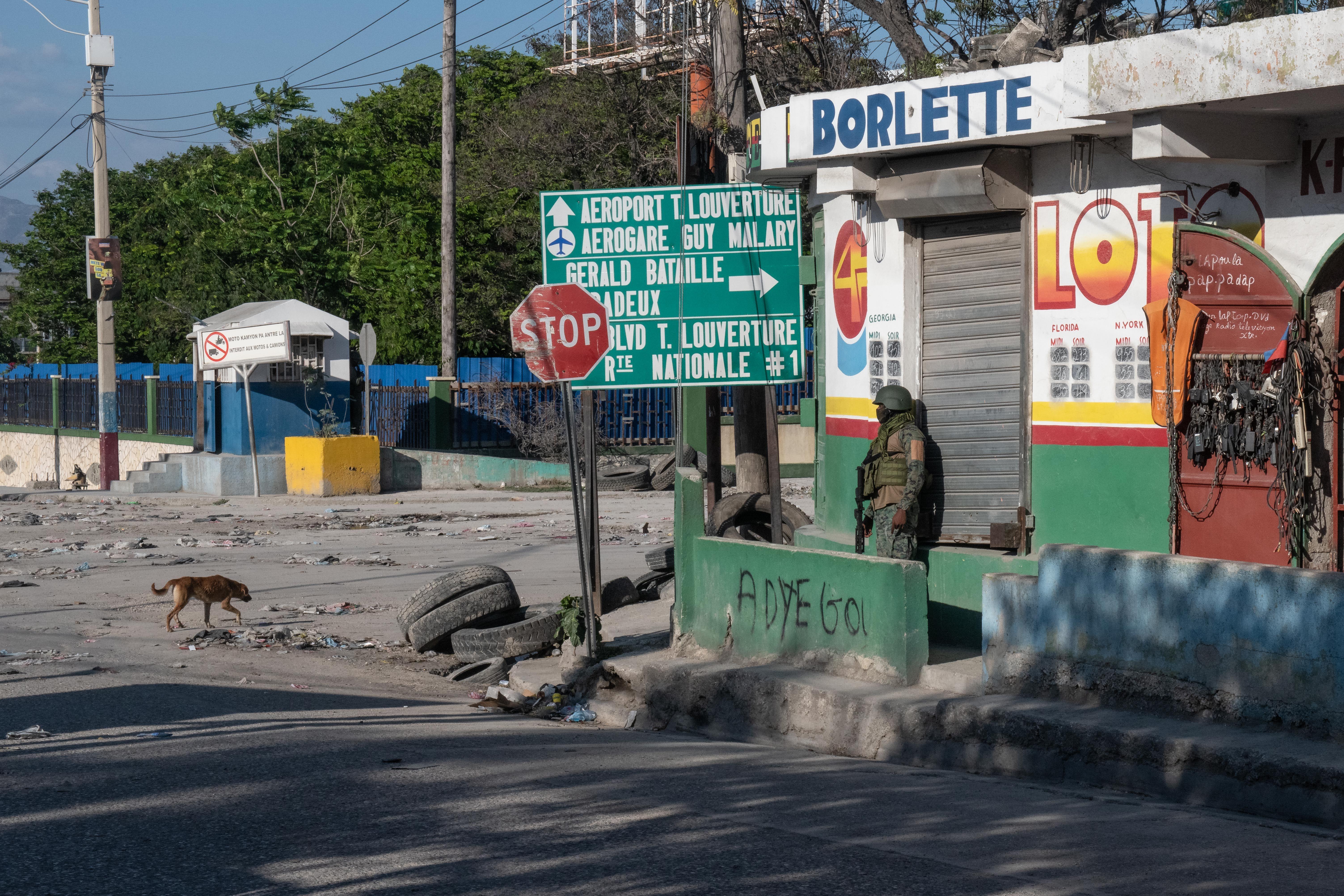 Un militar se apoya en la fachada de un edificio en una calle de Puerto Príncipe