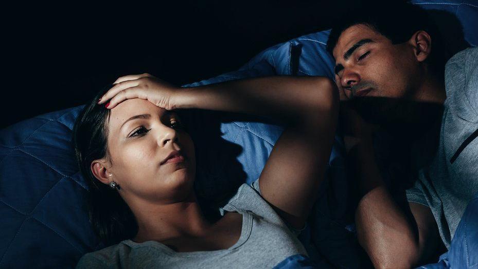 Una mujer molesta acostada en la cama con su novio roncando en casa en el dormitorio.
