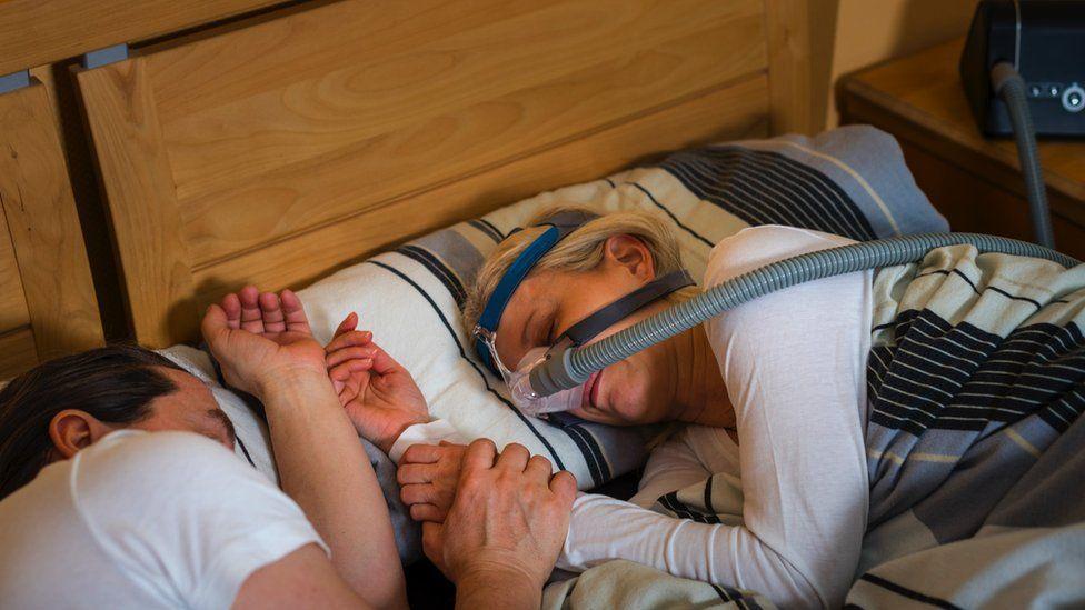 Una mujer durmiendo con una máquina CPAP.
