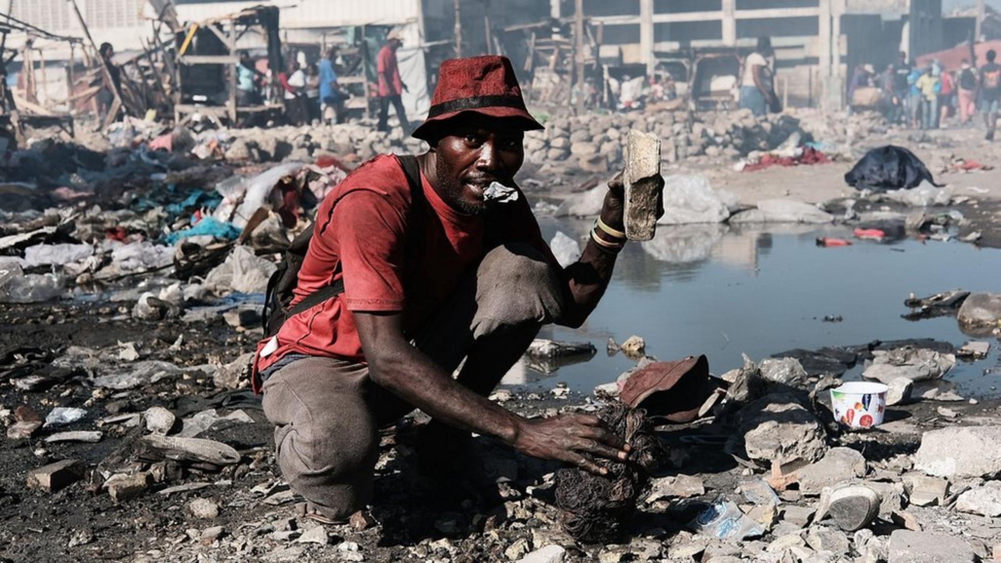 Un hombre junto a un montón de basura.