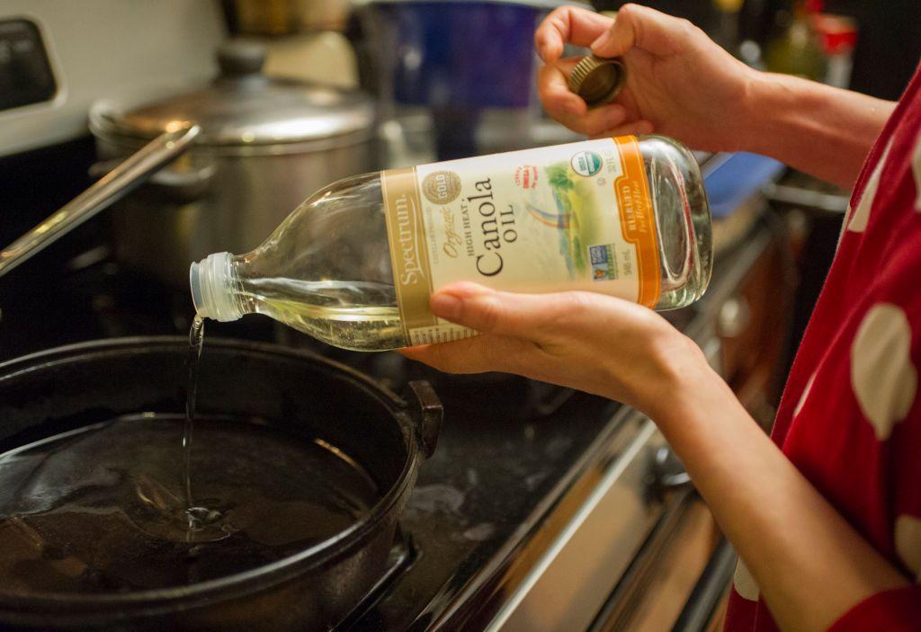 Una mujer echa aceite de canola a un sartén