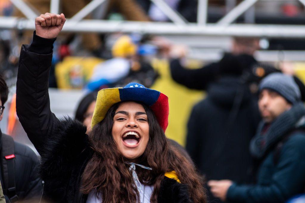 Una joven con el sombrero con los colores de Venezuela alza el puño en Madrid