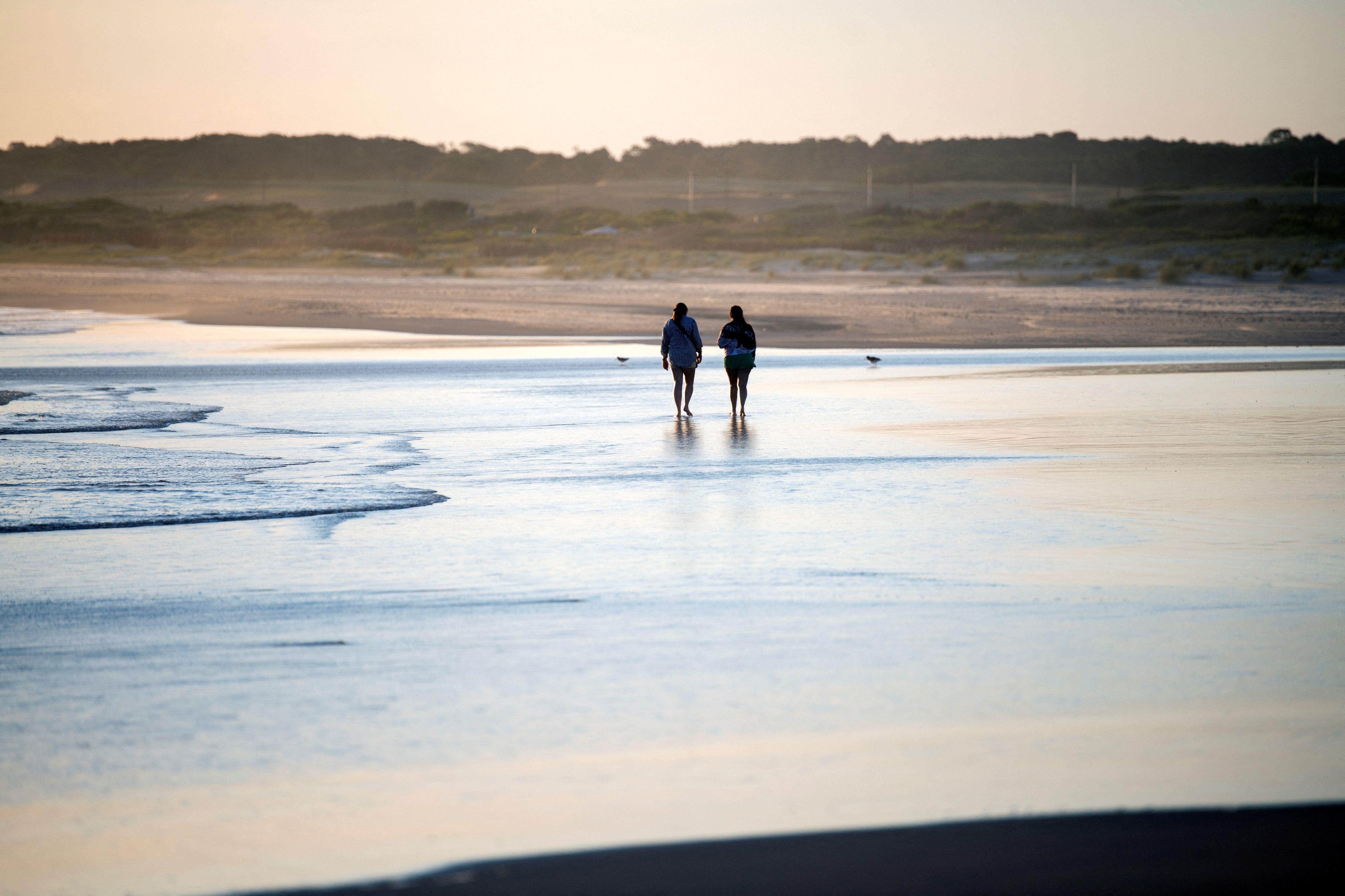 Dos personas caminan por una playa en Uruguay