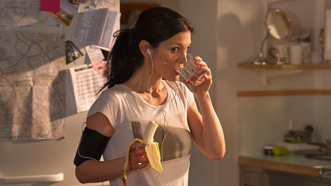 Una mujer desayuna una banana antes de entrenar