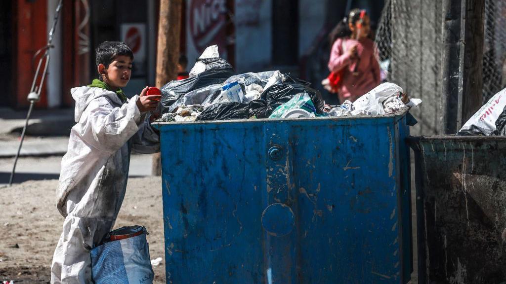 Un niño rebusca entre la basura