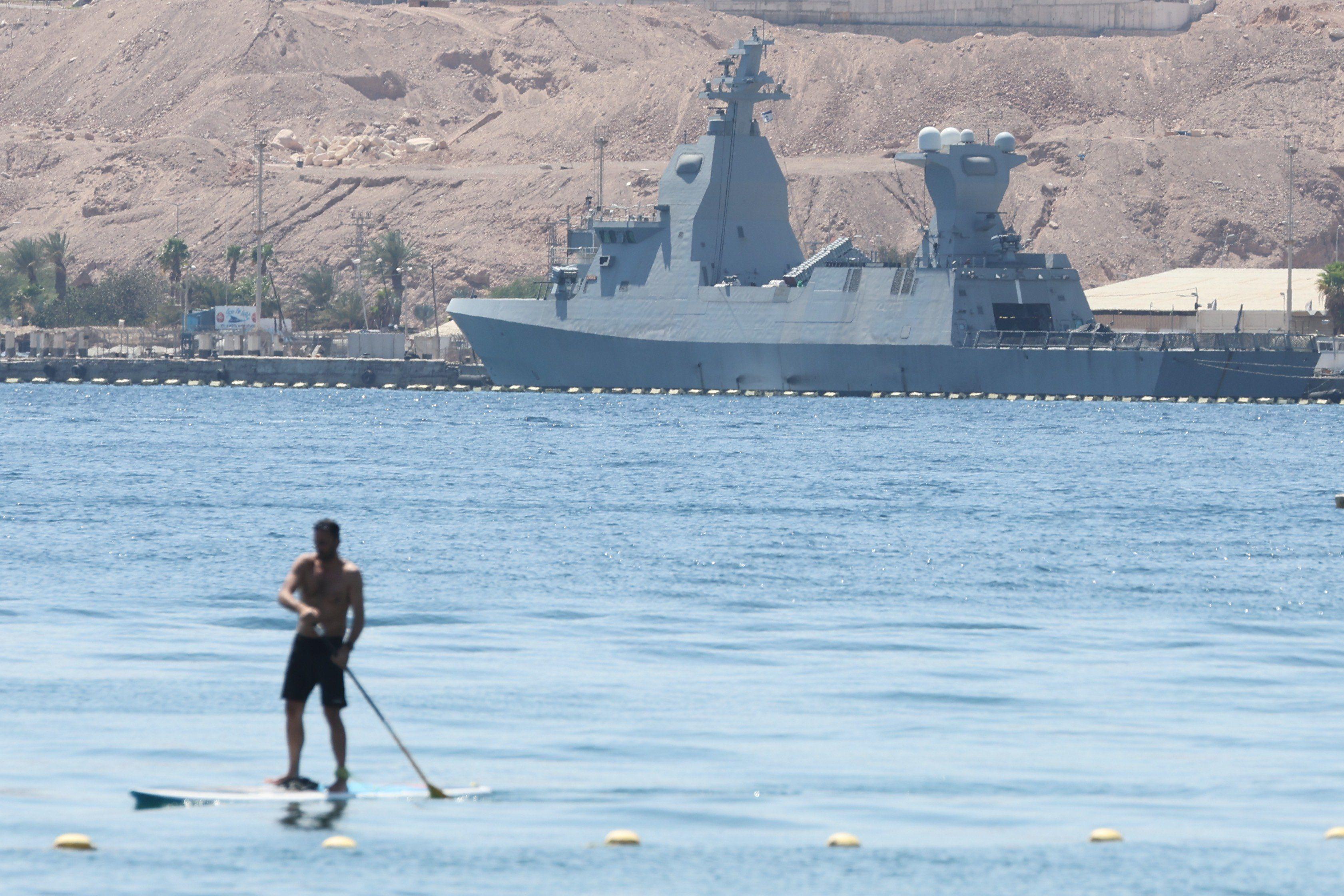 Un hombre rema frente a una corbeta clase Sa'ar 6 de fabricación alemana de la marina israelí atracada en la ciudad portuaria de Eilat, en el mar Rojo, el 16 de abril de 2024.