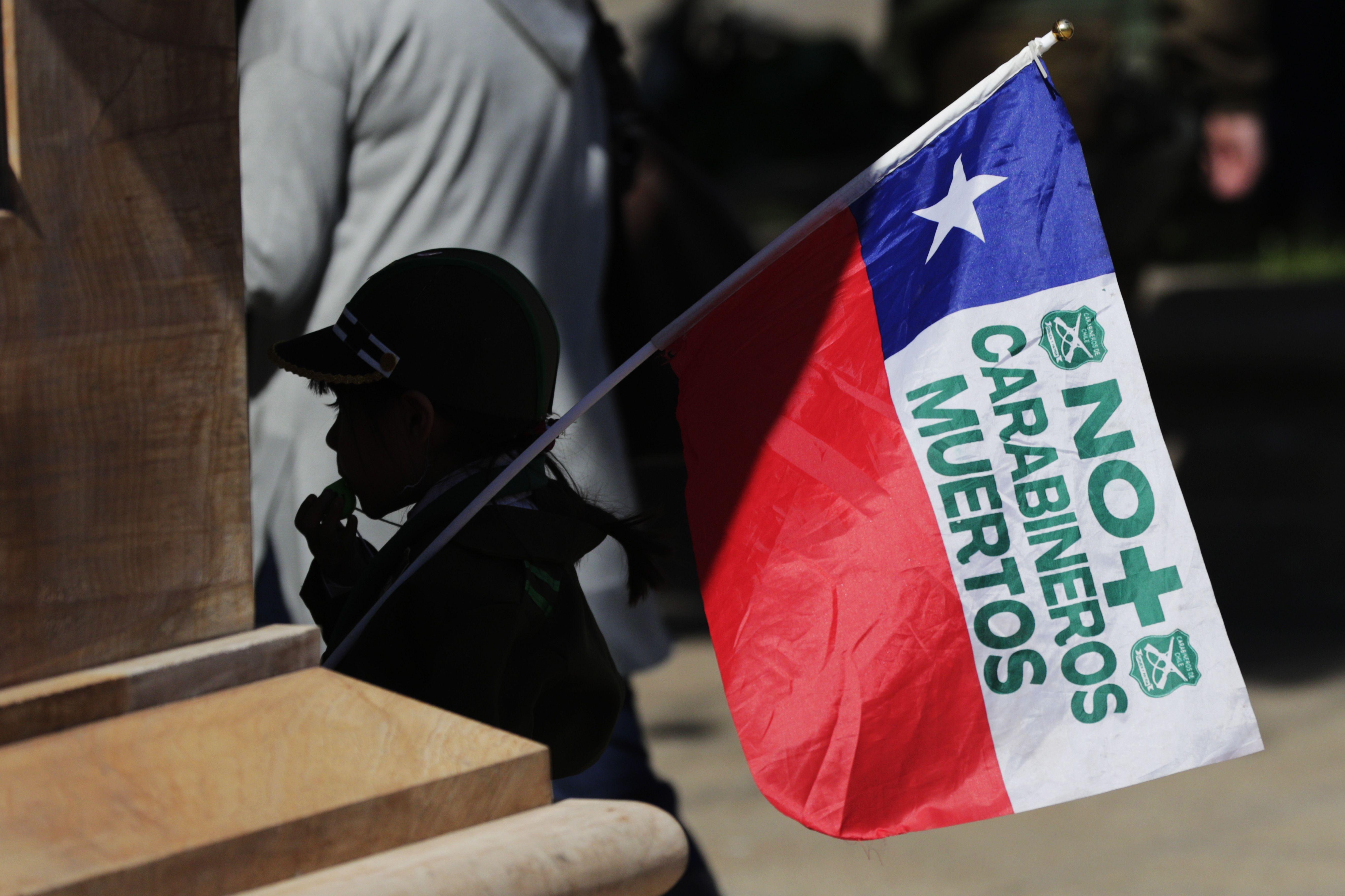 Una niña sujeta una bandera que dice "No más carabineros muertos"