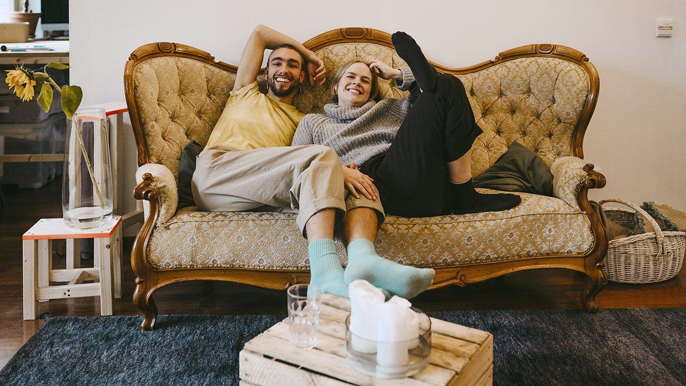 Una pareja ríe en el sofá.