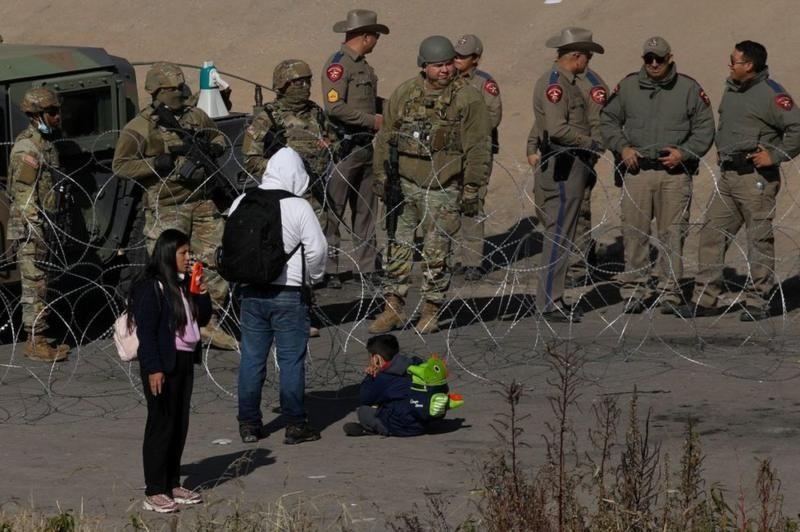 Migrantes piden la Guardia Nacional de Texas dejarles que se entreguen a la Patrulla Fronteriza en El Paso, Texas.