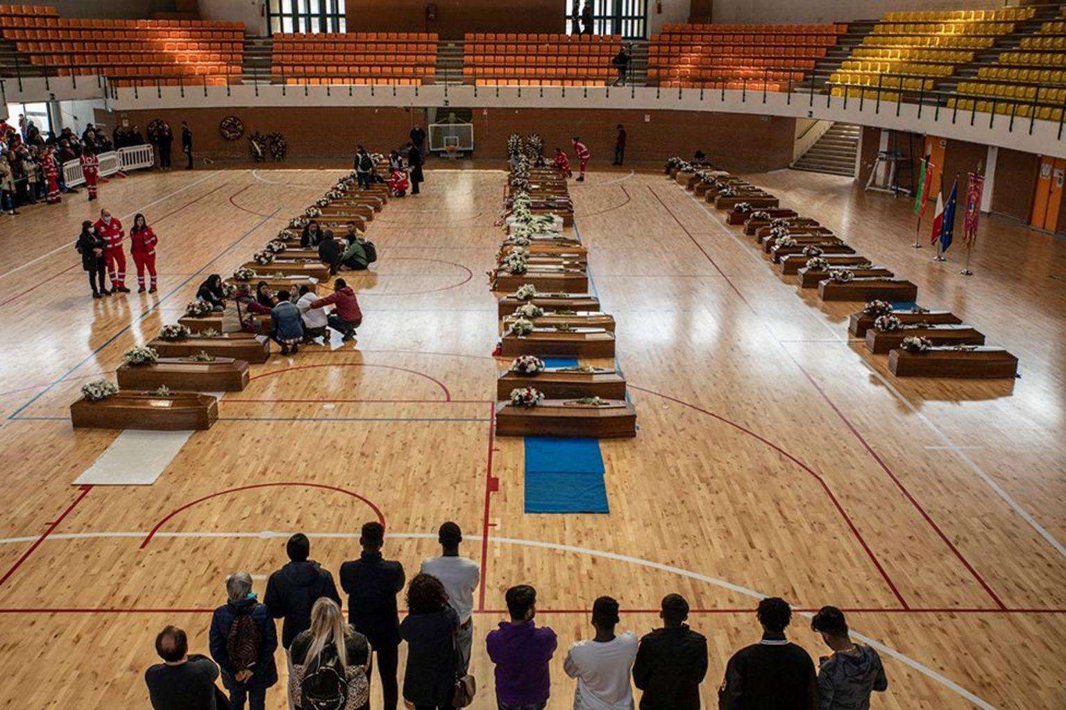 Ataúdes para los migrantes alineadas sobre el parqué de una cancha deportiva.