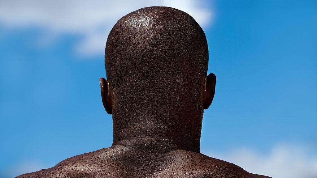 La cabeza de un hombre de espaldas a la cámara, con gotas de sudor