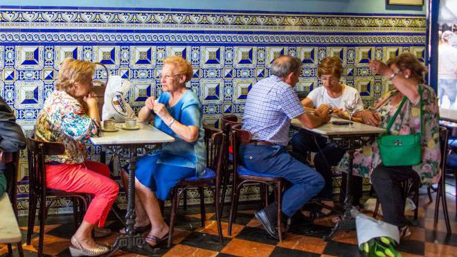 Dos grupos de personas de edad conversan en un bar de Bilbao.