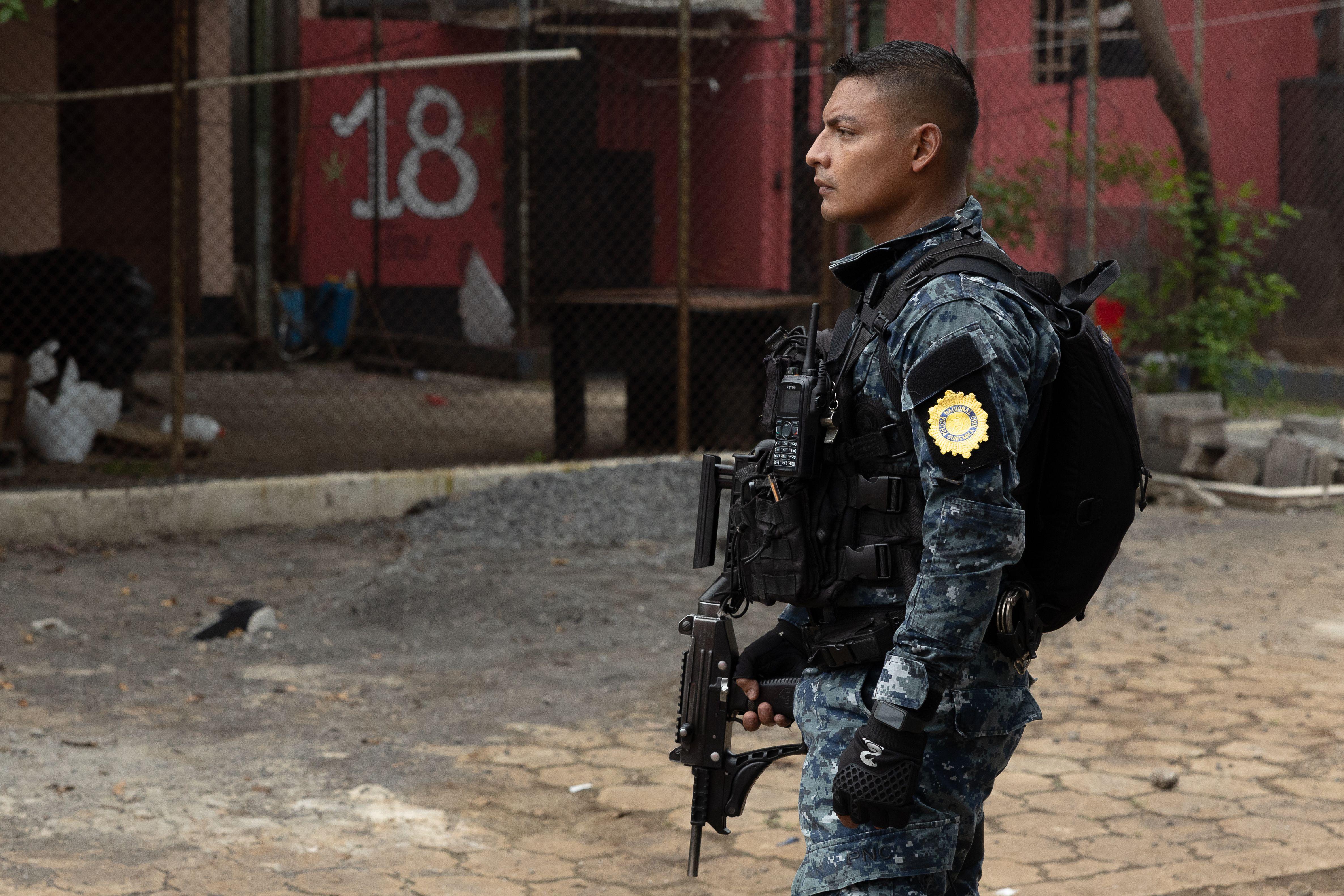 Un policía en el patio de la cárcel "El Infiernito" frente a un muro con el grafiti "18"