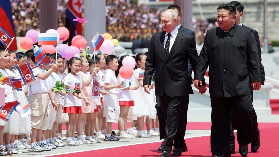 Vladimir Putin, presidente de Rusia, camina junto a su homólogo de Corea del Norte, Kim Jong-un, y pasan al lado de un grupo de niños.