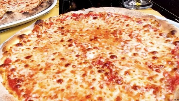 Una pizza recién hecha sobre la mesa, lista para ser disfrutada, combinando ingredientes irresistibles que deleitan los sentidos.