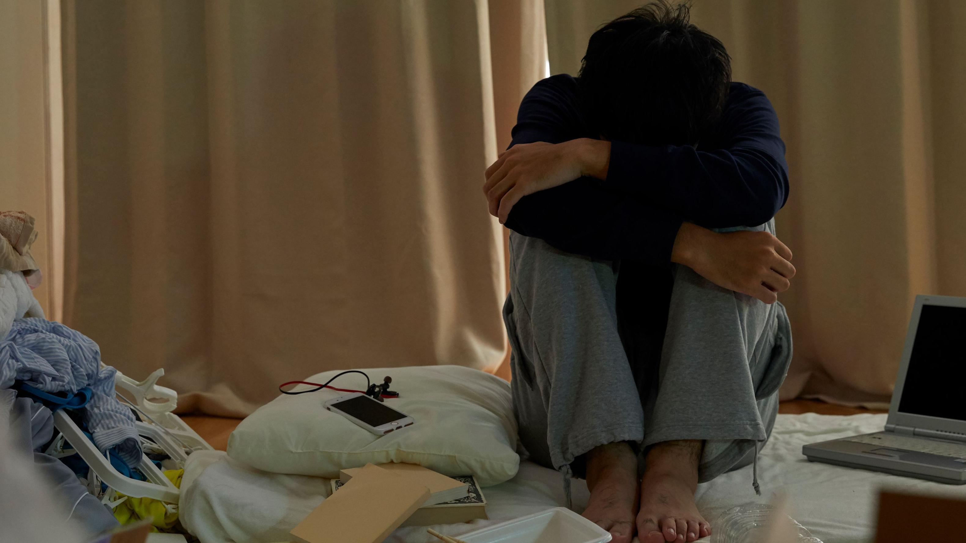 Un joven cabizbajo sentado en una cama