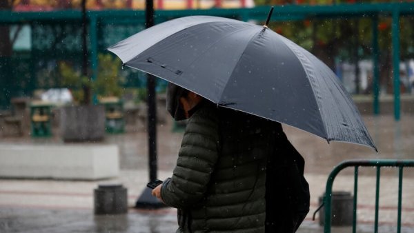Persona bajo la lluvia con paraguas. Advertencia por lluvias Meteorología.