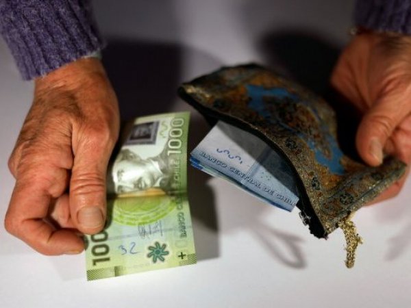 Dos ancianos alrededor de un frasco lleno de billetes, con las letras 