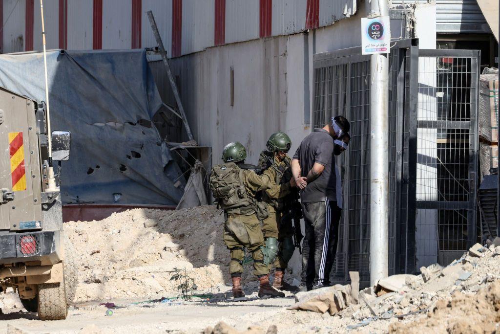 Dos militares israelíes junto a dos personas de civil maniatadas y con los ojos vendados.