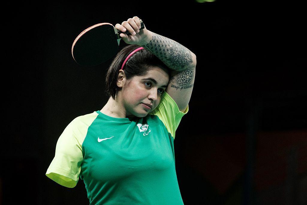 Bruna Costa Alexandre con un brazo levantado en una partida de tenis de mesa. Le falta el brazo derecho.