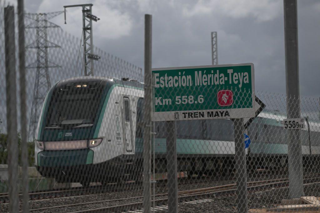 Un tren pasa junto a un cartel informativo.