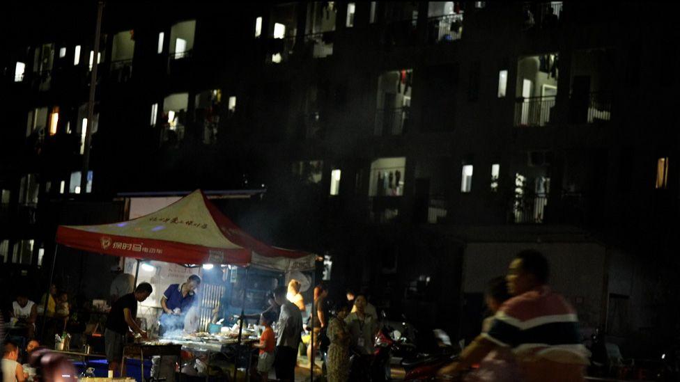 Un hombre vende comida frente a un edificio donde viven trabajadores.