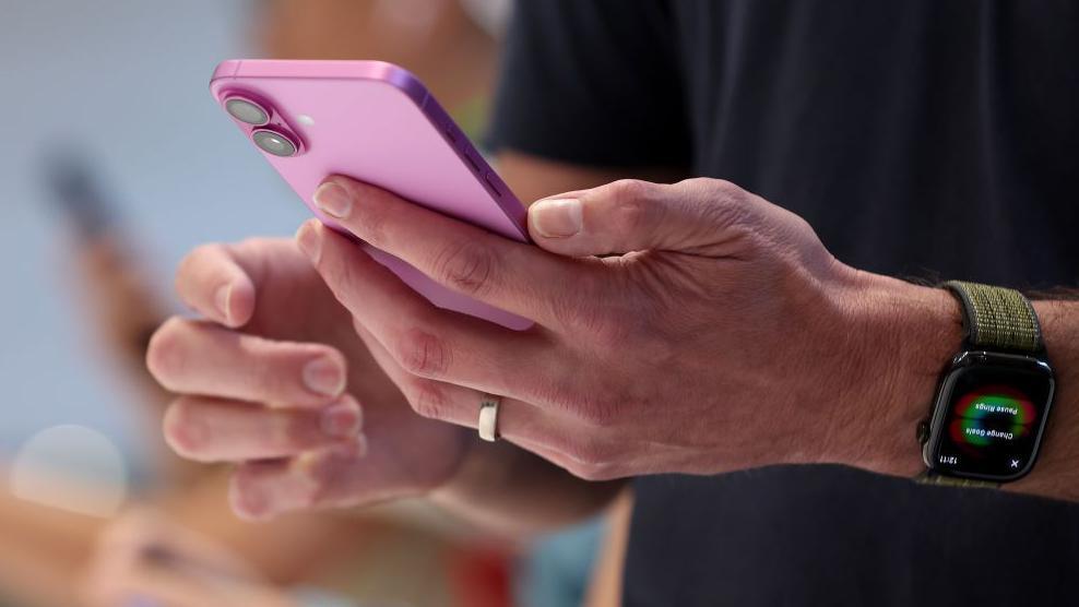 Un hombre con su Iphone en la mano.