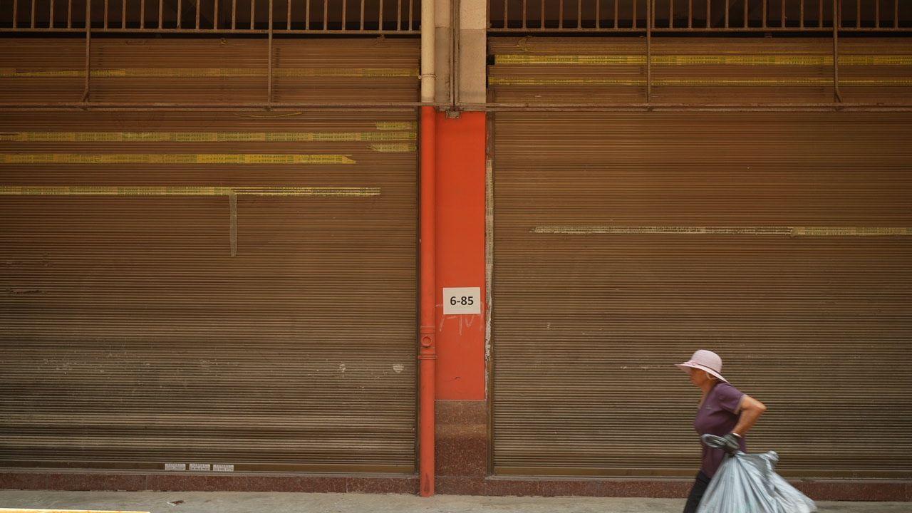 Una mujer pasa junto a tiendas cerradas en Ruili